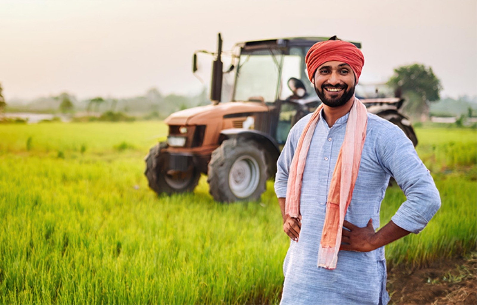 Farmer standing beside a tractor in a green field